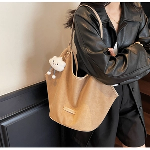 Detail of khaki tote bag featuring a plush cloud charm and stitched leather label