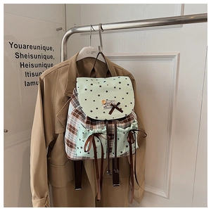 Detail of plaid backpack with mint green star flaps and decorative brown ribbon bows