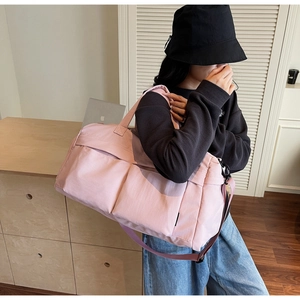 Pink waterproof travel duffel bag shown as a crossbody bag on a model for scale