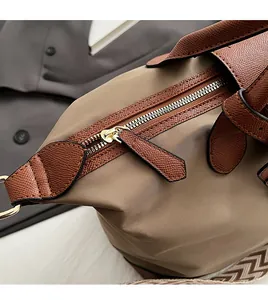 Detail of golden metal zipper and striped nylon strap on a multi-color tote bag