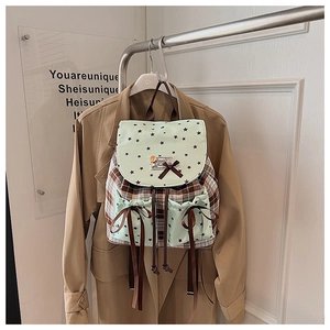 Detailed view of mint green plaid backpack featuring star patterns and ribbon bow detail