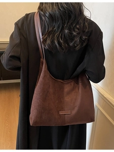 Grande borsa hobo in pelle scamosciata marrone indossata da modella in cappotto nero