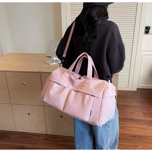 Back view of a large pink travel duffel bag carried as a crossbody with double handles