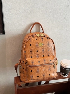 Brown faux leather backpack with rabbit prints and gold studs on a wooden shelf