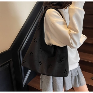 Detailed close-up of hollow flower laser cut design on black faux suede tote bag