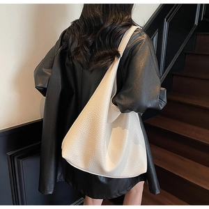 Close-up of white lychee grain leather tote bag worn by a model in a modern interior