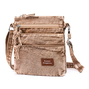 Close-up of vintage washed denim crossbody bag with multiple zippers and leather patch
