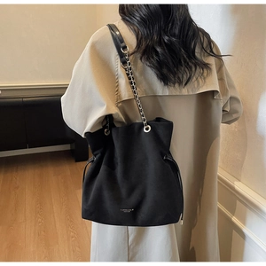 Détail du sac seau noir en cuir mat avec bandoulière chaîne et cordon de serrage