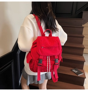 Primer plano de mochila de nailon rojo con cierre de solapa y hebillas negras en escalera