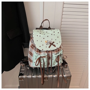 Detail of checkered canvas backpack with star pattern and silk bow accents on a suitcase