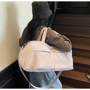 Pink travel duffel bag with side zipper pocket and adjustable straps on wooden stairs