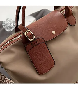 Detail of beige nylon tote bag with brown leather flap and removable card holder charm
