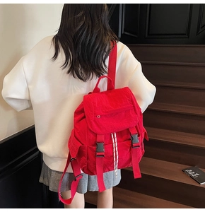 Close-up of red nylon backpack featuring adjustable buckle straps and drawstring closure
