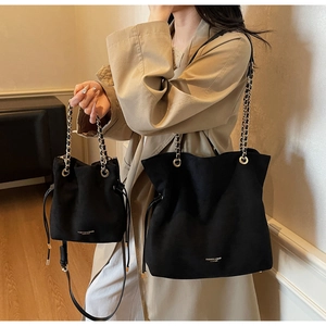 Détail de l'ensemble sac seau et cabas en cuir noir mat avec chaîne en métal et logo