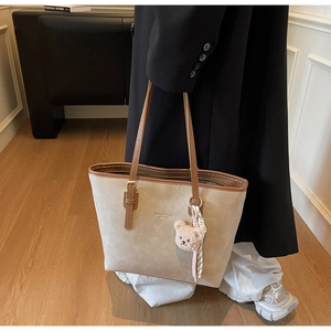 Chic beige tote bag with brown straps, cute plush bear charm and striped scarf detail