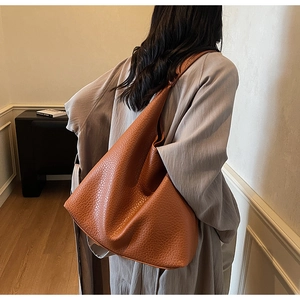 Brown leather hobo tote bag worn by model showing large capacity and soft texture