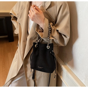 Détail d'un sac seau noir avec cordon de serrage, chaîne dorée et logo élégant