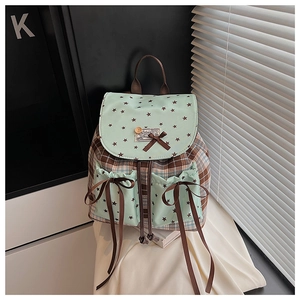 Detail of star print and brown plaid fabric backpack with bow and button accents