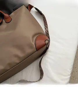 Close-up of reinforced brown leather corners and stitching on khaki nylon tote bag