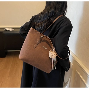 Brown faux suede tote bag featuring a cute plush bear pendant and elegant shoulder straps