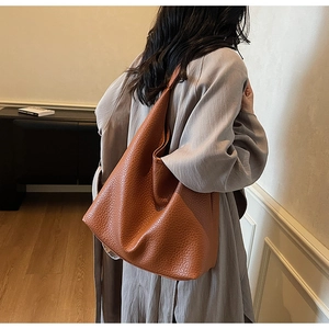 Detailed texture of caramel brown lychee grain leather on a large slouchy hobo tote bag