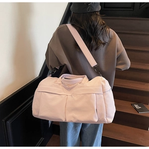Rear view of model carrying pink travel bag with shoulder strap on modern stairs