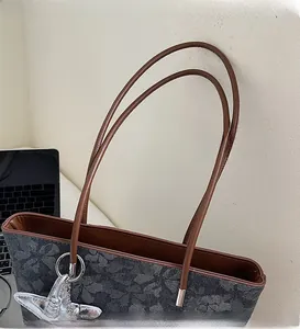 Close-up of brown leather straps and grey floral pattern on a stylish tote bag