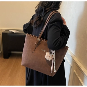Brown faux suede tote bag with teddy bear charm and striped scarf detail on model
