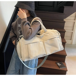 Close-up of cream travel bag with dual handles and adjustable strap on stairs