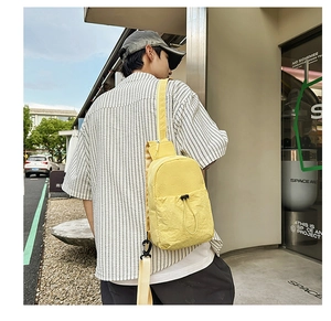 Detailed macro view of yellow nylon chest bag with zipper and adjustable black strap