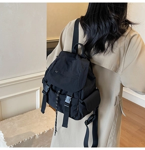 Detail of black nylon backpack featuring a flap closure and YOU R BEAR side label