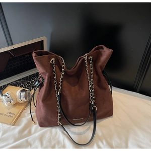 Détail du sac cabas en daim marron foncé avec bandoulière chaîne et lettrage blanc
