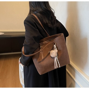 Brown faux leather tote bag with MIKAXIO logo, plush bear charm and striped ribbon detail