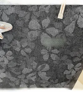 Detail of floral jacquard fabric on a black tote bag with silver butterfly hardware