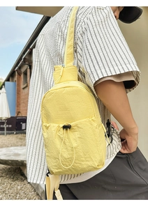 Detail of light yellow crinkled nylon sling bag with adjustable black drawstring pocket
