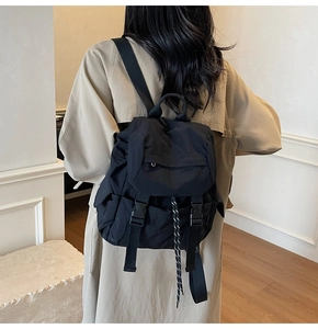 Detail view of a black minimalist nylon backpack with dual buckle straps for daily use