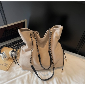 Détail du sac cabas en daim beige avec cordon noir et bandoulière en chaîne dorée