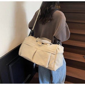 Close-up of beige travel bag with large front pockets and adjustable shoulder strap