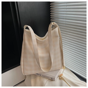 Dettaglio della borsa tote a quadretti beige con ciondolo di perle a fiore su libro d'arte