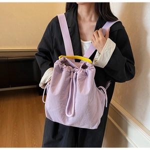 Dettaglio zaino a secchiello viola chiaro con manico intrecciato giallo e chiusura a cordoncino