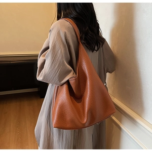 Close-up of brown pebbled leather tote bag with wide strap for underarm wear