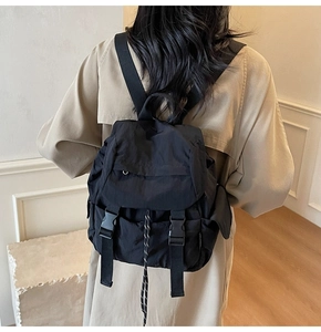 Model wearing a black waterproof nylon backpack with secure buckle closure and drawstring