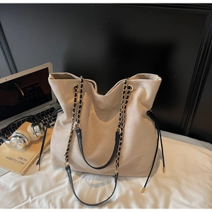 Vue détaillée d'un sac seau en daim beige avec chaîne, ordinateur portable et livres