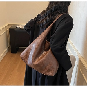 Brown lychee leather tote bag shown from a side view on a model for daily commute