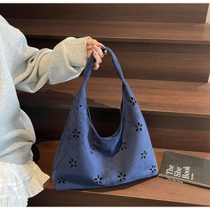Detail view of navy blue suede shoulder bag with intricate laser-cut hollow flower patterns