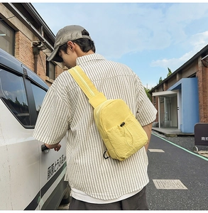 Detail of yellow nylon sling bag with drawstring pocket on street style background