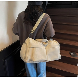 Detail view of large travel duffel bag showing side shoe compartment and wide shoulder strap