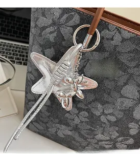 Detail of silver balloon dog and star keychain charm on a floral jacquard tote bag