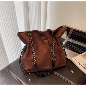 Détail du sac seau en daim marron foncé avec bandoulière chaîne et cordon de serrage