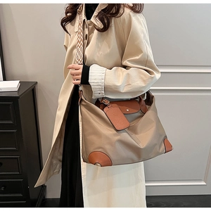 Detail of khaki nylon tote bag with brown leather accents and a woven jacquard strap